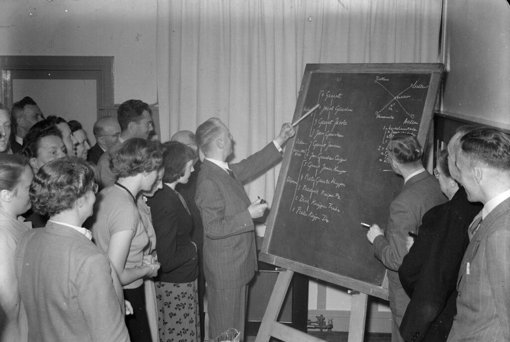 Dominee Pieter Kuijper, die een causerie hield voor de Nederlandse Genealogische Vereniging, wees aan de hand van het schoolbord op de bijzonderheden van de stamboom van het geslacht Kuijper. De leden van de Vereniging en de vele genodigden volgden aandachtig zijn uiteenzetting.